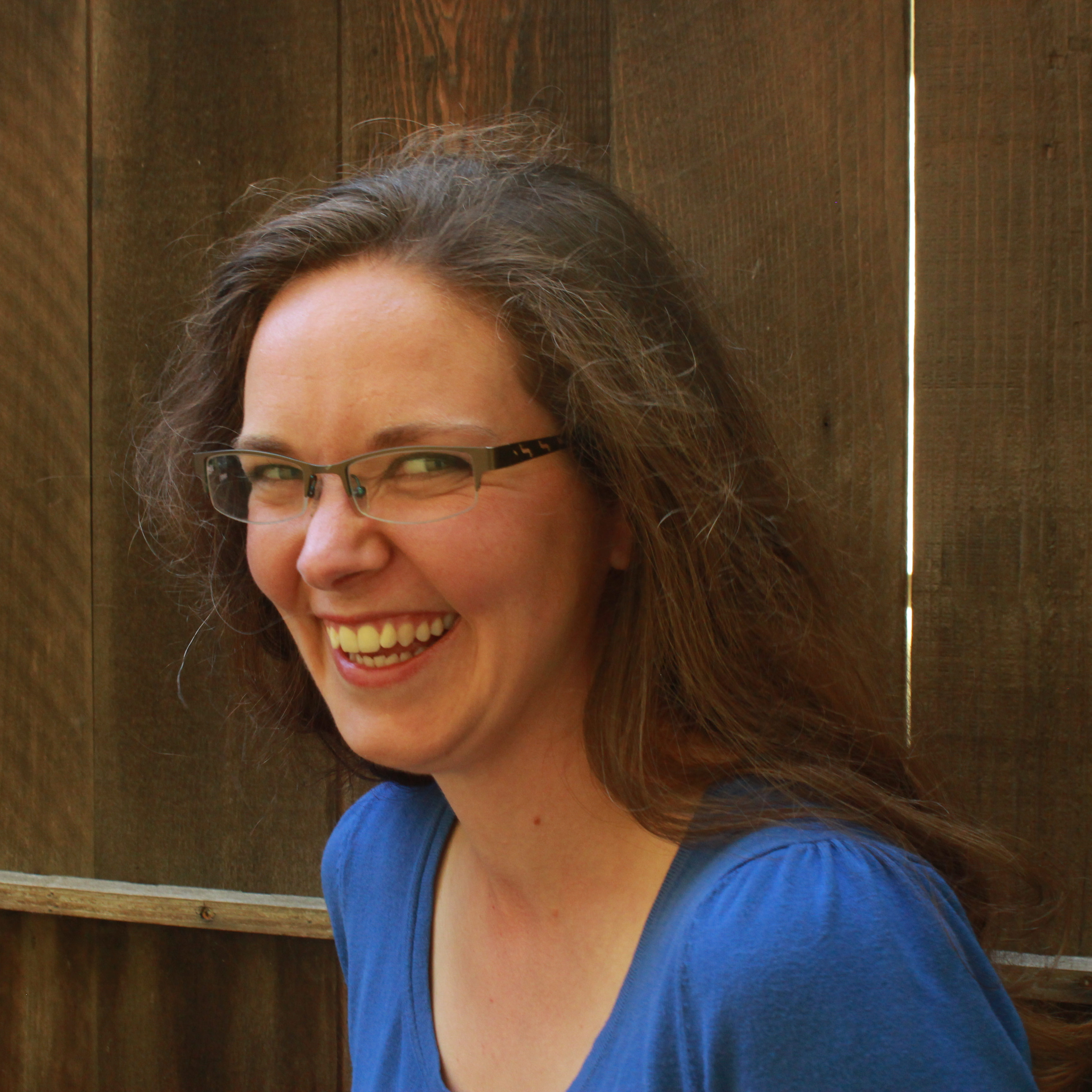 Mary Ruppert laughing in front of a wooden fence